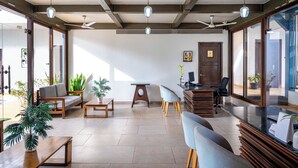 A spacious lobby with a reception desk, seating area, and large windows. - The Ivy Anjuna (Anjuna)