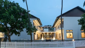 A modern two-story house with a white picket fence, a pool, and a sign that reads "The Ivy Arjuna." - The Ivy Anjuna (Anjuna)
