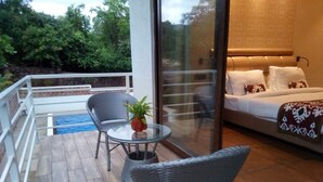 A balcony with wicker chairs, a glass table, and a potted plant. - The Ivy Anjuna (Anjuna)