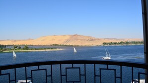Vista de un río con barcos y un paisaje arenoso al fondo.