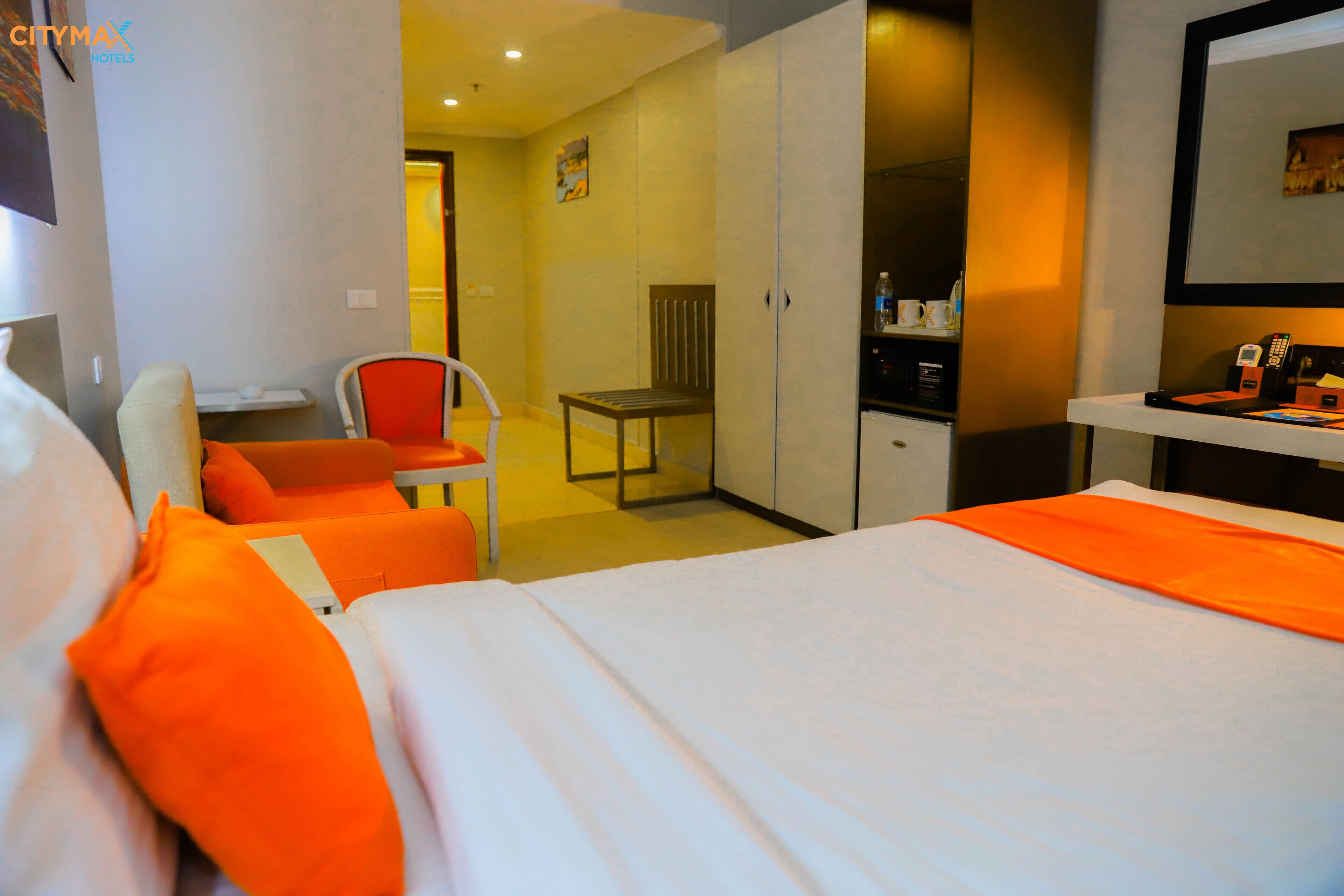 A hotel room with a bed, a desk, a chair, and a wardrobe.