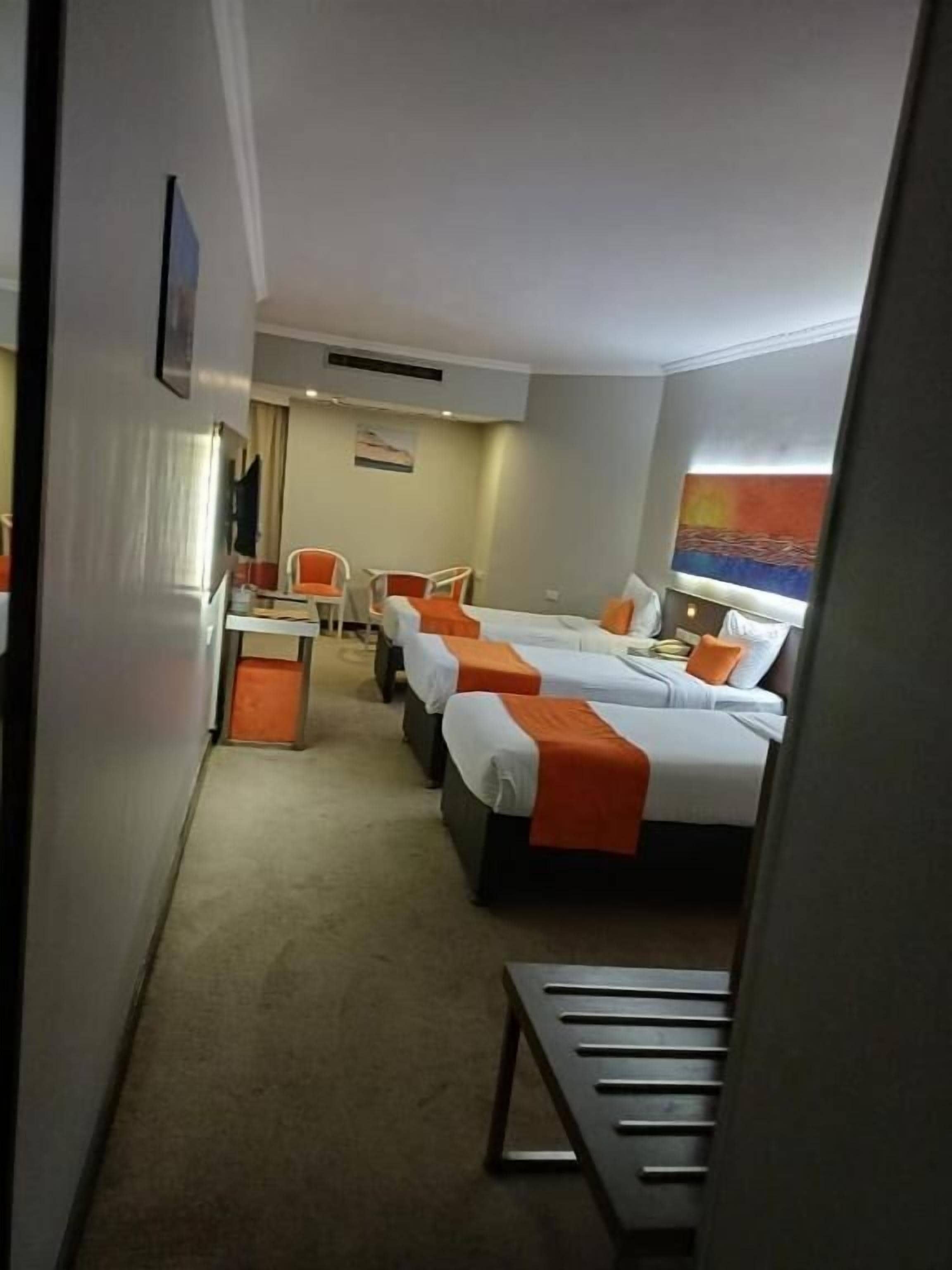 Habitación de hotel con dos camas, un escritorio y una silla.