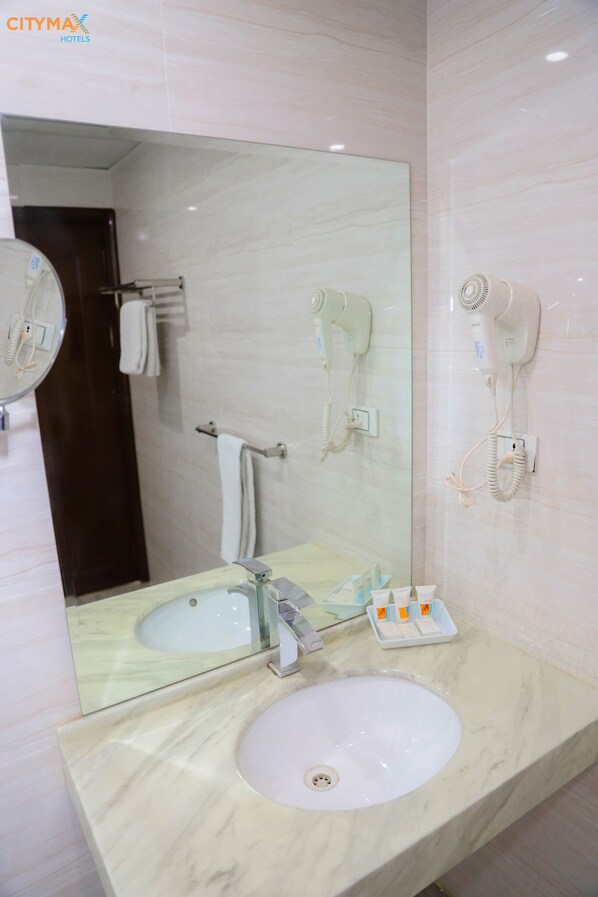A bathroom with a marble sink, a large mirror, a hairdryer mounted on the wall, and a towel rack.