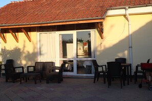 A patio area with outdoor furniture, a sliding glass door, and a tiled roof. - Galeria In The Garden (Plovdiv)