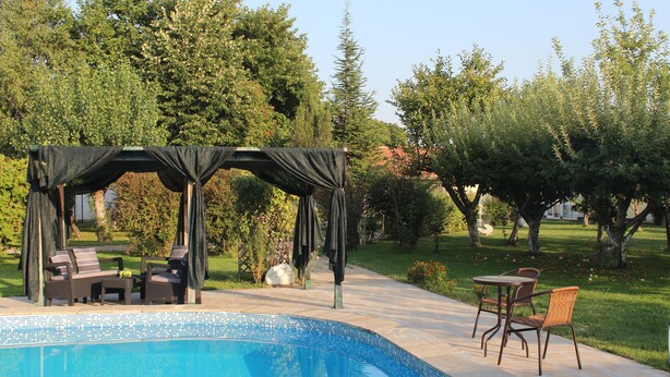 A pool area with a gazebo, lounge chairs, and a table. - Galeria In The Garden (Plovdiv)