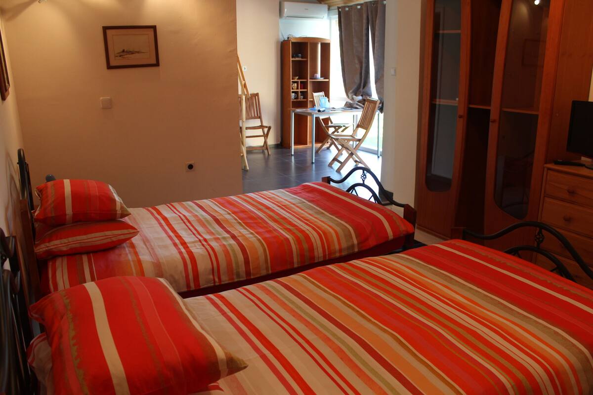 A bedroom with two beds, a desk, and a chair.