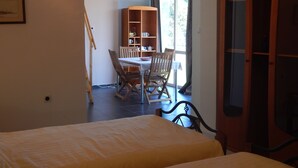 A bedroom with a bed, a wooden table with chairs, and a bookshelf. - Galeria In The Garden (Plovdiv)