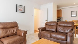 A living room with two brown leather sofas, a wooden coffee table, and framed artwork on the walls. - Ferncourt (Dublin)