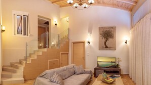 A living room with a sofa, a coffee table with fruit, a TV, and a staircase. - Ionian Heaven Villas (Lefkada)