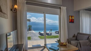 A modern living room with a large sliding glass door leading to an outdoor patio with a pool and seating area. - Ionian Heaven Villas (Lefkada)