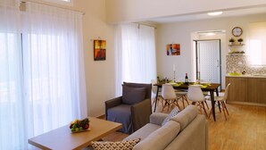 A spacious living area with a wooden ceiling, a dining table with chairs, a sofa, and a kitchen area in the background. - Ionian Heaven Villas (Lefkada)