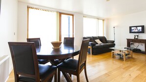 Un salon moderne comprenant une table à manger, des chaises, un canapé et un téléviseur.