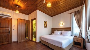 A bedroom with a wooden ceiling, a bed with white bedding, a nightstand, and a wall-mounted light fixture. - Armistis Hotel (Mudanya)