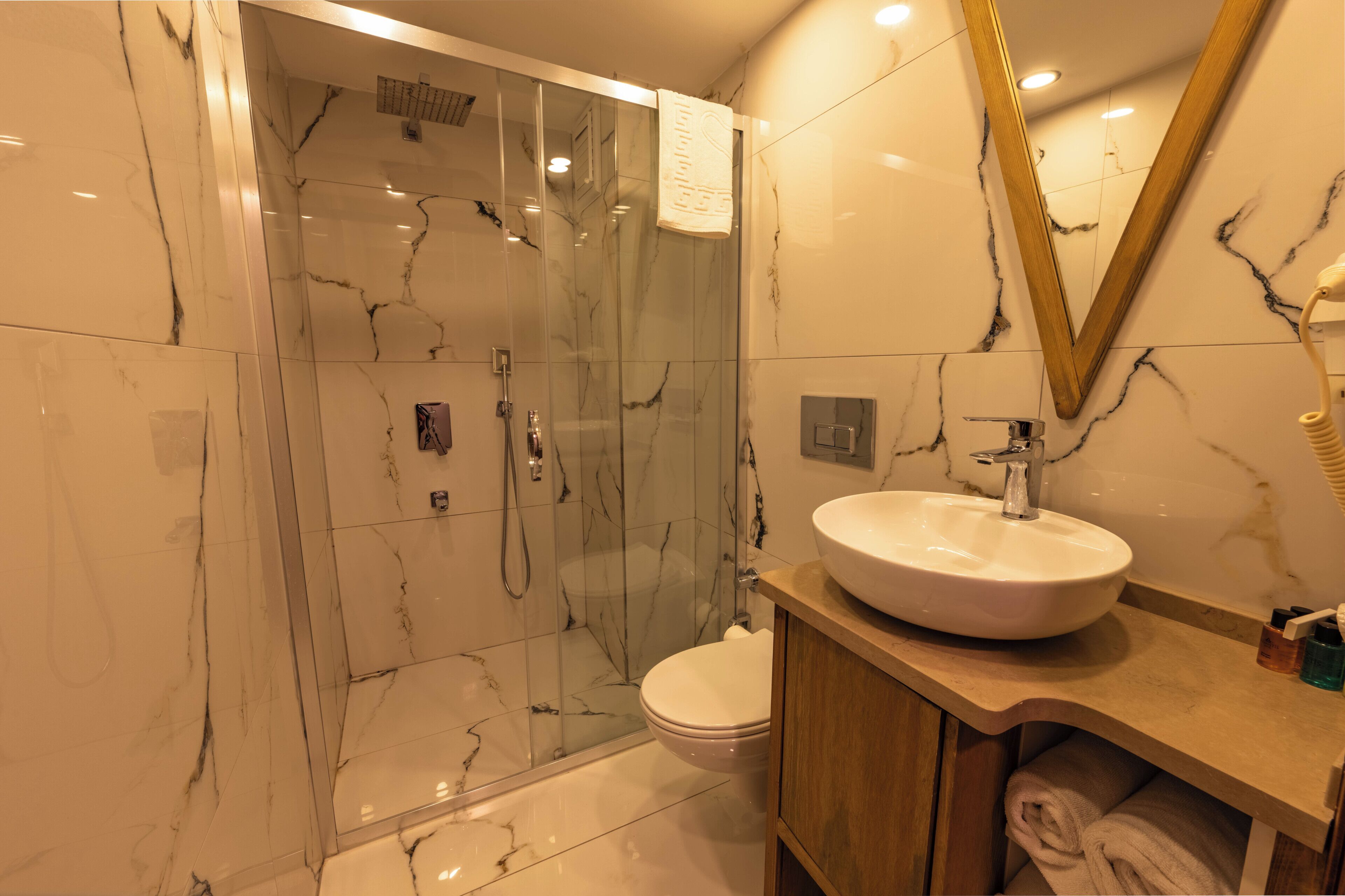 Une salle de bain avec une douche à parois de verre, un lavabo blanc et un meuble-lavabo en bois.