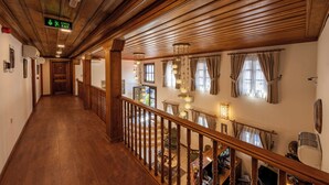 A wooden interior with a staircase, a hallway, and a dining area with tables and chairs. - Armistis Hotel (Mudanya)