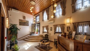 A spacious living area with a wooden ceiling, a staircase leading to an upper level, and a reception desk. - Armistis Hotel (Mudanya)