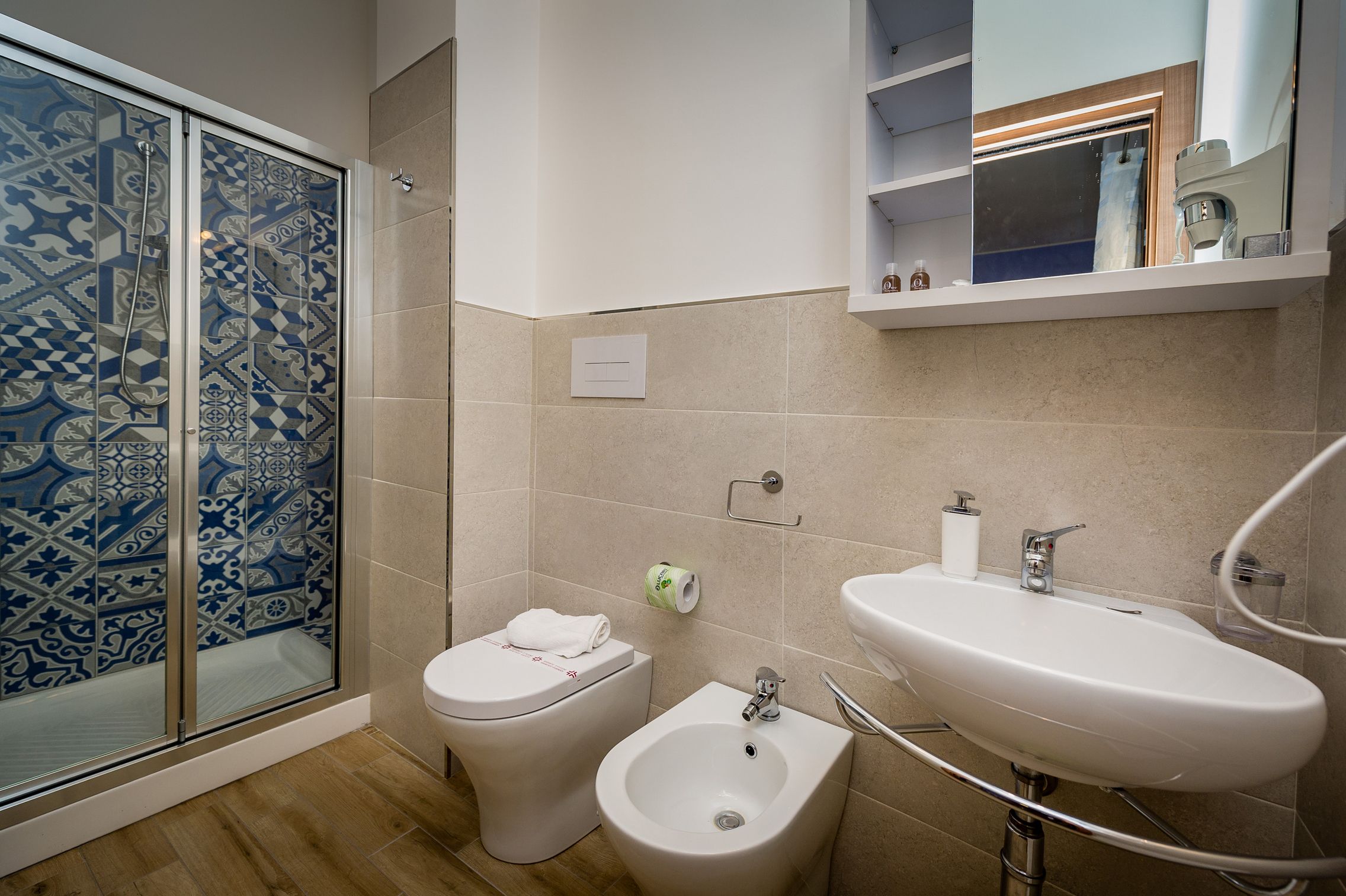 A bathroom with a shower, toilet, bidet, and sink.