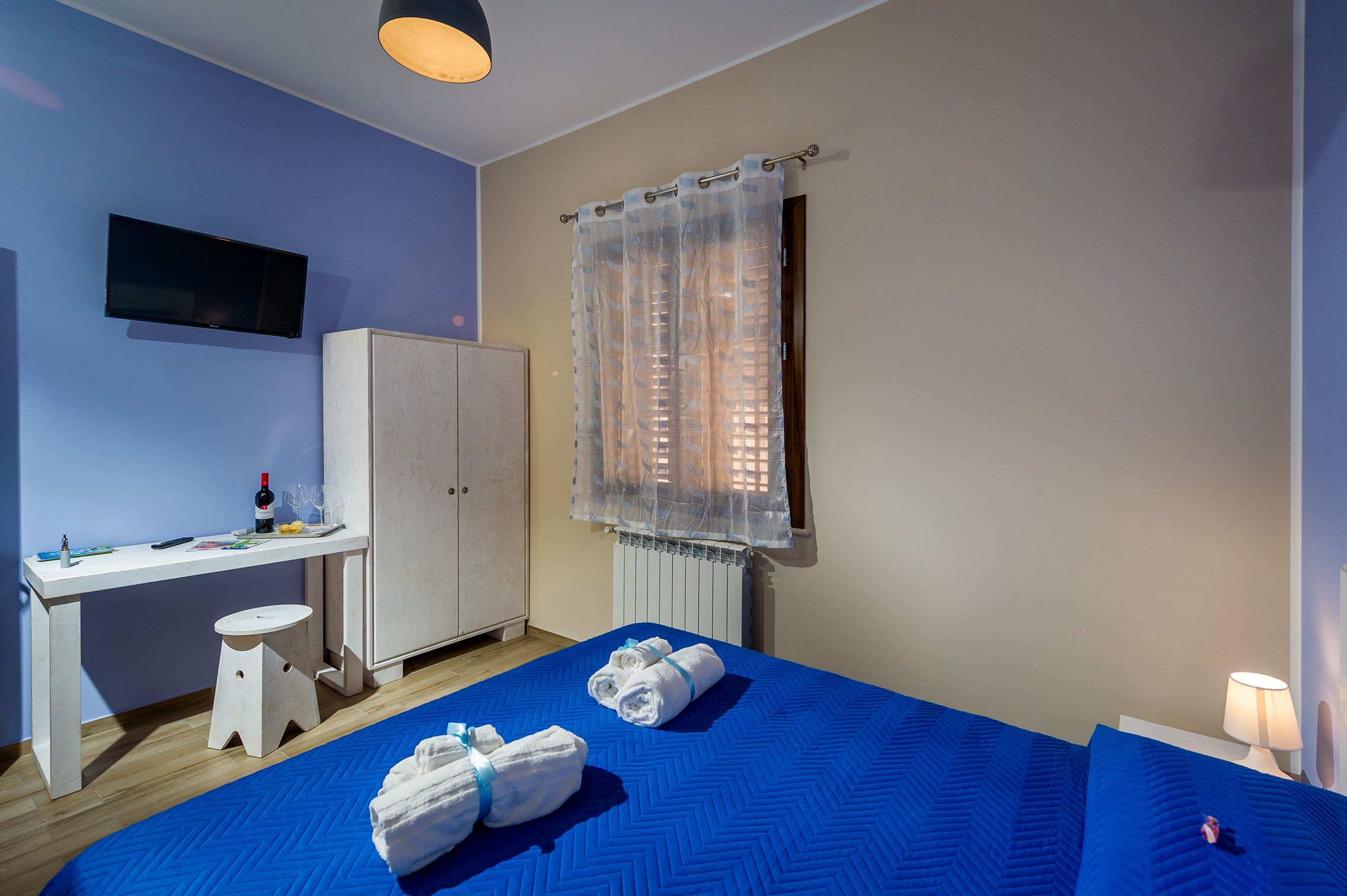 A bedroom with a bed, a desk, and a wardrobe.