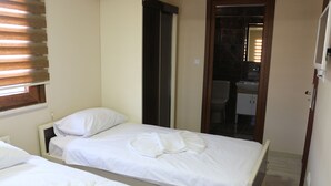 A hotel room with two single beds, a bathroom with a sink and mirror, and a wooden door leading to another room. - Beyoglu Huzur Hotel (Istanbul)