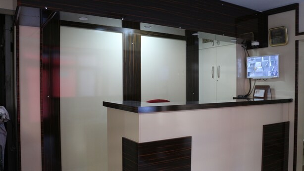 A modern reception desk with a flat-screen TV, a coat rack, and a framed certificate on the wall. - Beyoglu Huzur Hotel (Istanbul)