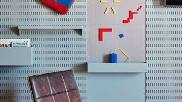 A room with a pegboard wall, a leather chair, a small table, and a hanging bag.
