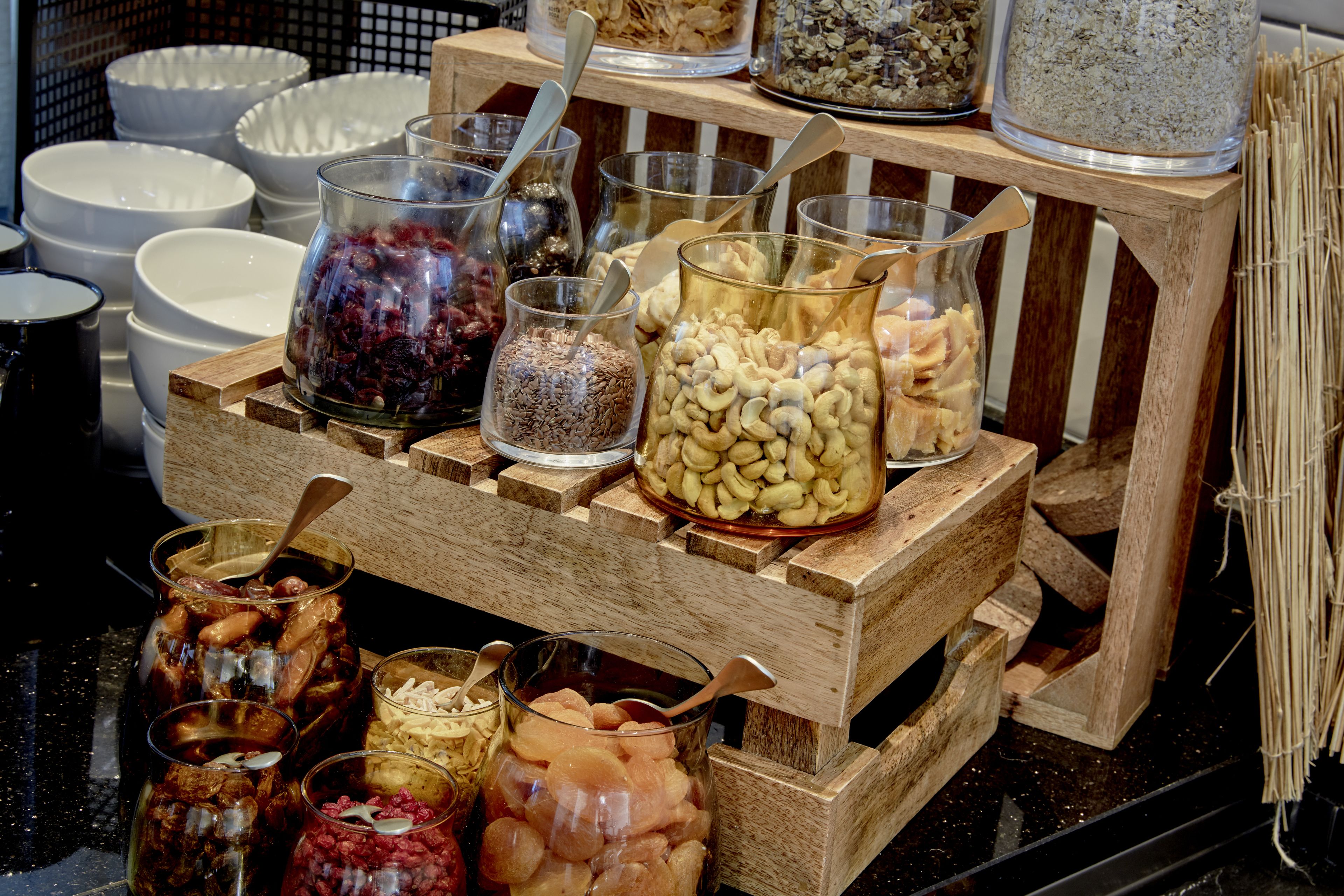 Un expositor de madera con diversos productos alimenticios como frutos secos, frutas deshidratadas y cereales.