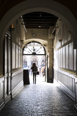 A corridor with a cobblestone floor, arched ceiling, and large windows at the end. - Apartments Rynek Glowny (Kraków)