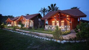 A row of wooden cabins with pitched roofs, each with a porch and a small garden area. - Nerissa Hotel - Special Class (Kemer)