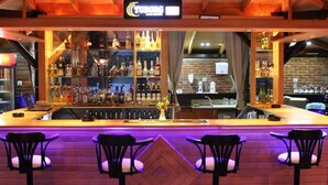 A bar area with a wooden counter, multiple shelves of bottles, and bar stools. - Nerissa Hotel - Special Class (Kemer)