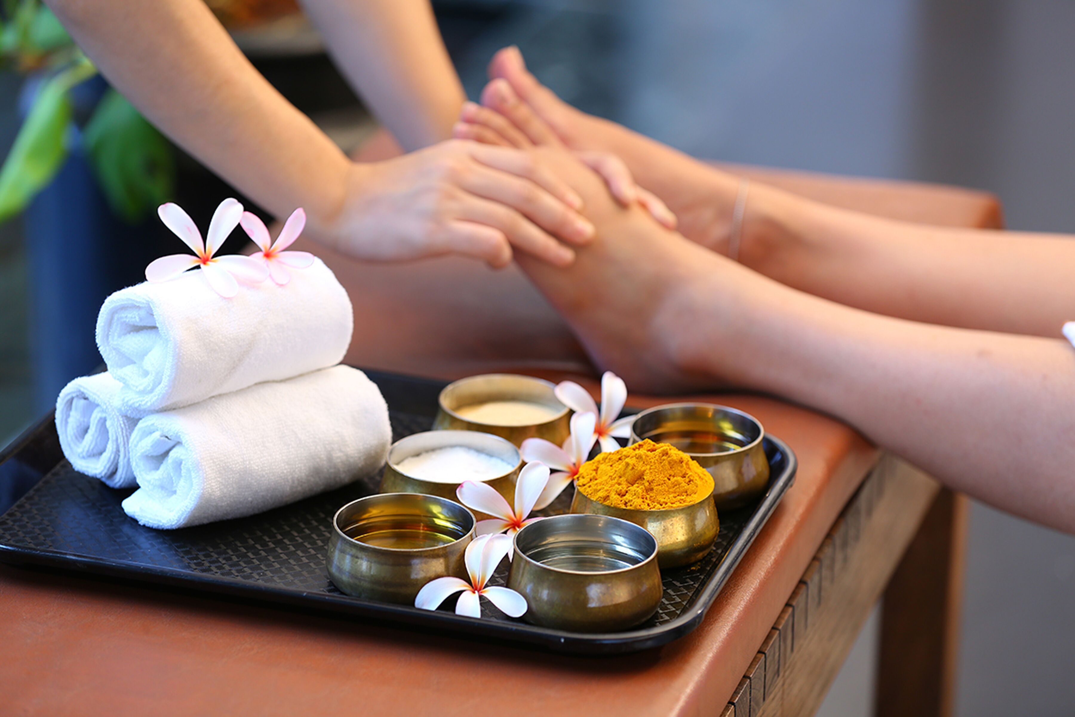 A tray with rolled towels, small bowls of cream, and yellow powder, likely for a spa treatment.