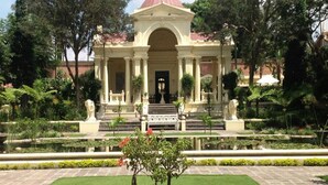 A building with a central entrance, flanked by columns, and a symmetrical garden with a fountain. - Thamel Trekkers Hotel (Kathmandu)