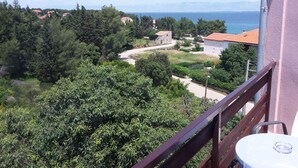 A balcony with a view of a coastal village, including houses, trees, and a road leading to the sea. - Villa Stari dvor (Preko)
