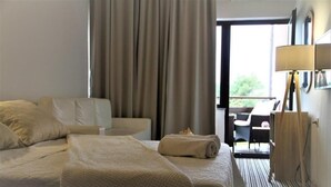 A hotel room with a large bed, a desk, a chair, and a view of the outdoors through a window. - Villa Stari dvor (Preko)