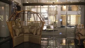 Un hall d’entrée moderne avec une cloison en verre, un canapé d’angle et une vue sur la rue.