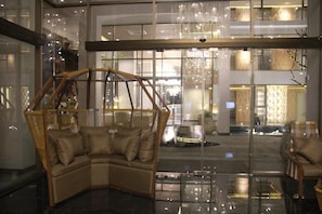 A modern lobby with a glass partition, a corner sofa, and a view of the street. - Stay With Nimman Chiang Mai (Chiang Mai)