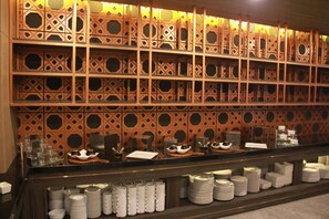 A hotel reception area with a wooden decorative wall, a counter with stacked plates and glasses, and a mirror reflecting the wall. - Stay With Nimman Chiang Mai (Chiang Mai)