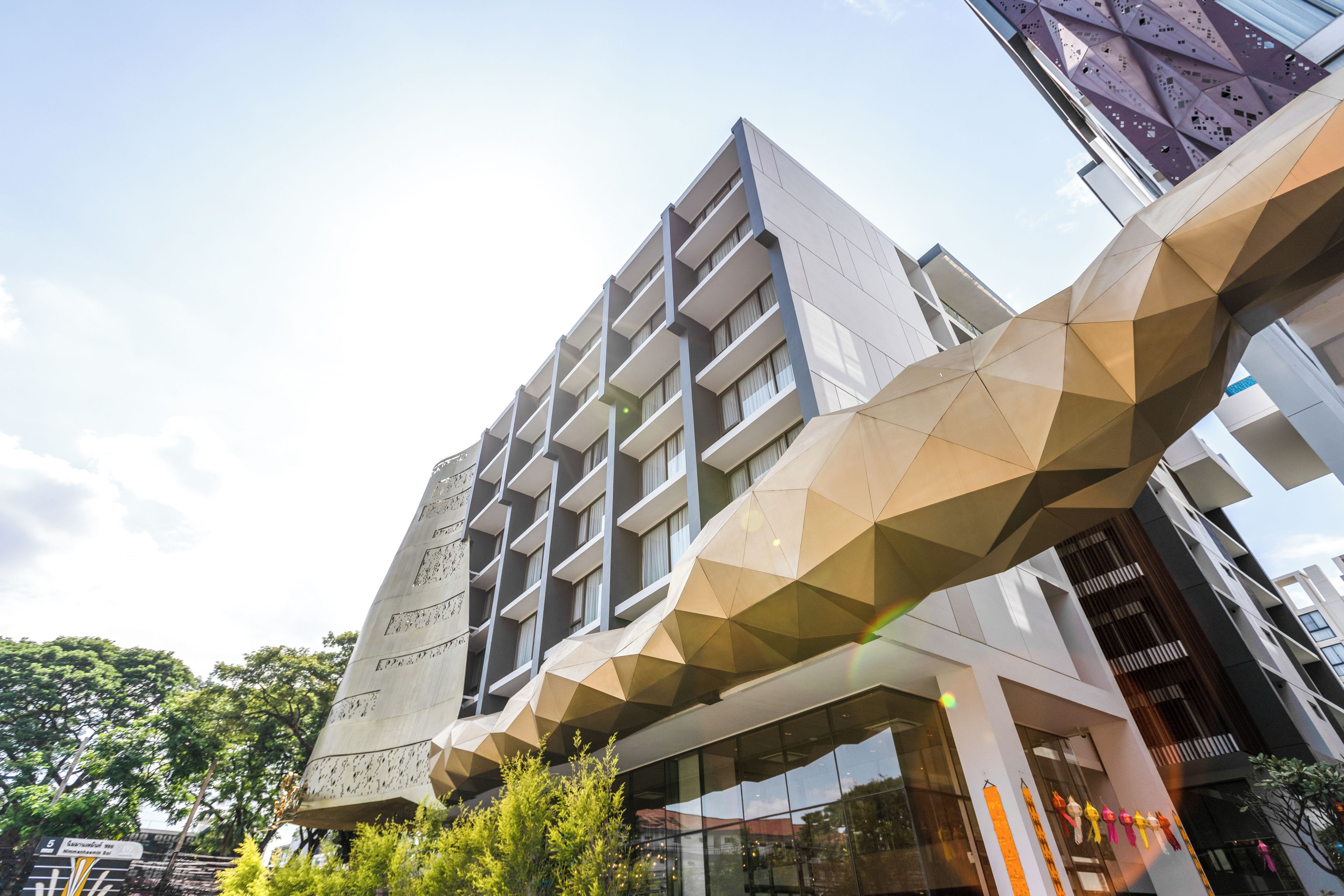 A modern building with a geometric facade, multiple balconies, and a glass entrance.
