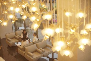 A lobby with sofas and tables, a chandelier, and a view of the outside. - Stay With Nimman Chiang Mai (Chiang Mai)