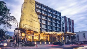 Un hotel modern amb una façana corba singular, múltiples balcons i una entrada ben il·luminada.