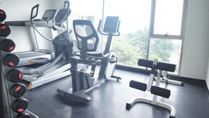 Une salle de sport équipée de tapis de course, d’un vélo d’appartement et d’un banc de musculation.