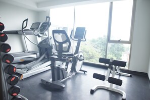 Et fitnessrum med løbebånd, motionscykel og bænkpress.