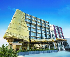 A hotel with a unique architectural design, featuring a large, triangular structure on the left and a multi-story building with balconies on the right. - Stay With Nimman Chiang Mai (Chiang Mai)
