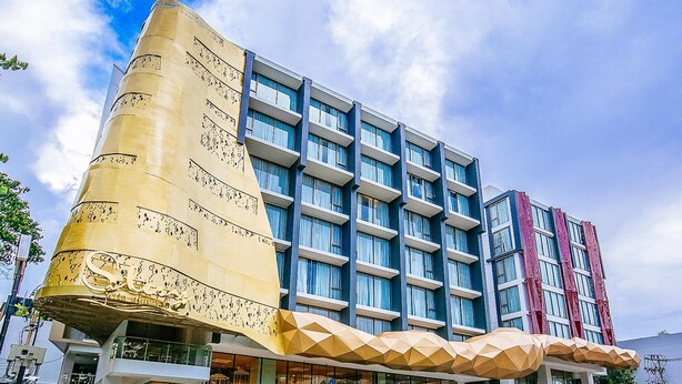 Un hôtel moderne doté d’une architecture originale, caractérisé par une imposante structure dorée et de nombreux balcons.