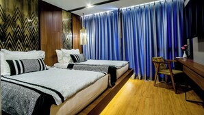 Une chambre d’hôtel avec deux lits, un bureau, une chaise et un rideau.