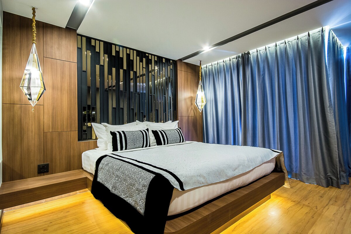 A modern bedroom with a bed, wooden paneling, and a view of the outdoors.
