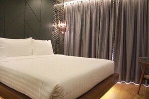 A neatly made bed with white linens, a patterned wall, and a modern light fixture. - Stay With Nimman Chiang Mai (Chiang Mai)