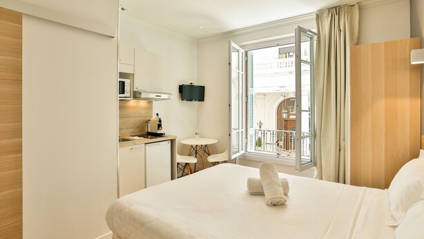 Une chambre d’hôtel équipée d’un lit, d’un bureau, d’une chaise, d’une télévision et d’une fenêtre avec des rideaux.
