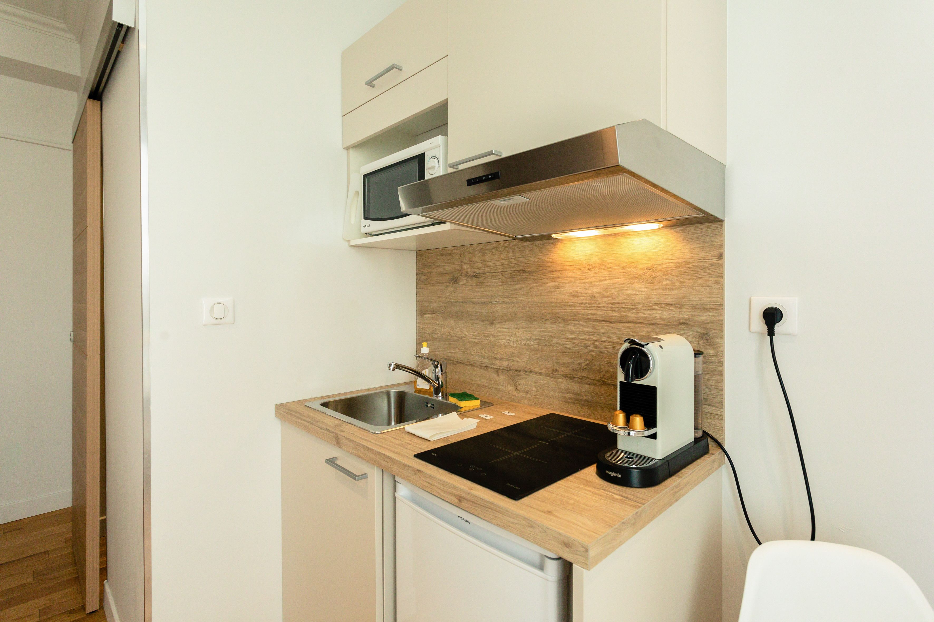 Een kleine keuken met een magnetron, fornuis en koffiezetapparaat.