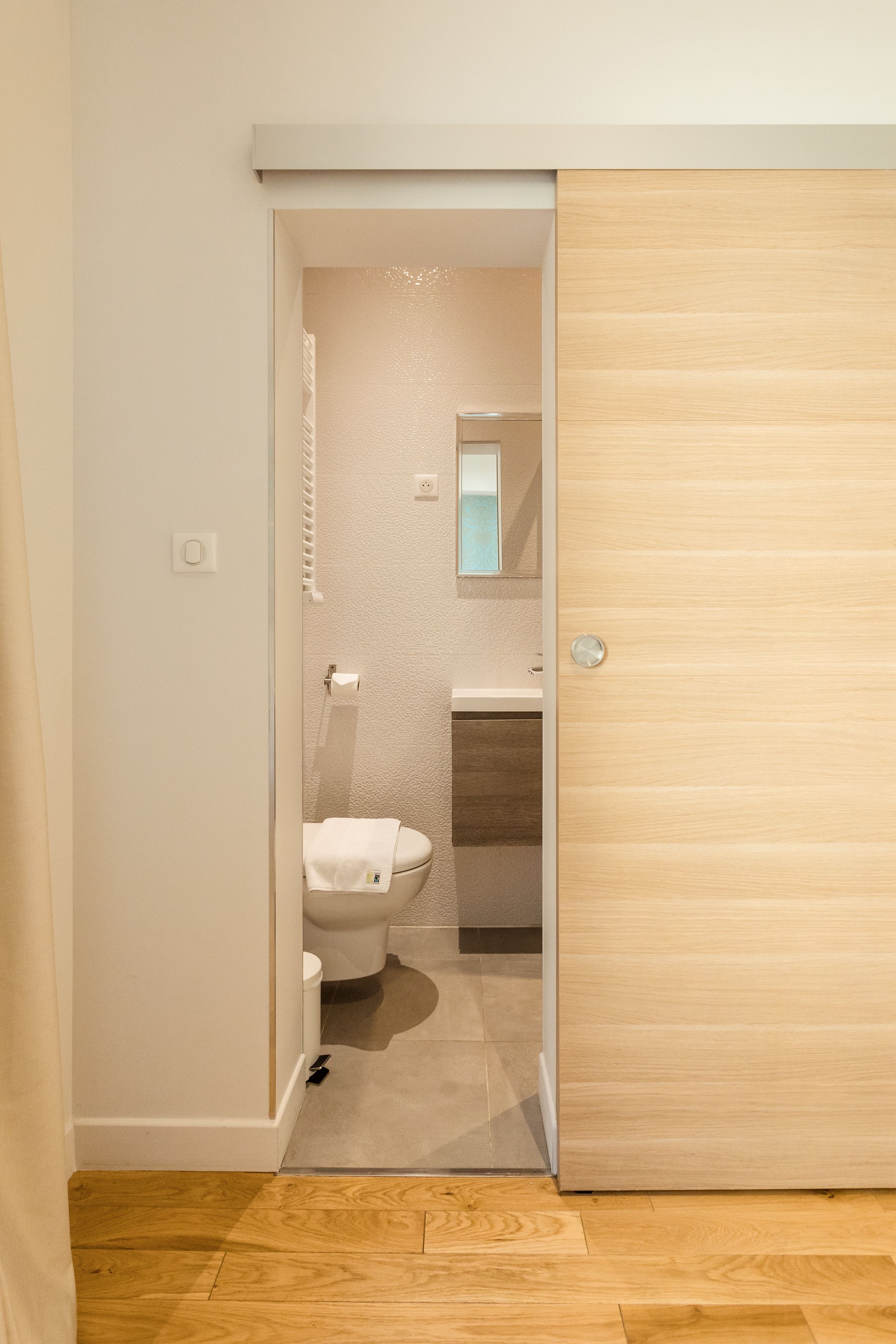 Een moderne badkamer met toilet, wastafel en spiegel.