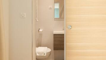 Een moderne badkamer met toilet, wastafel en spiegel.